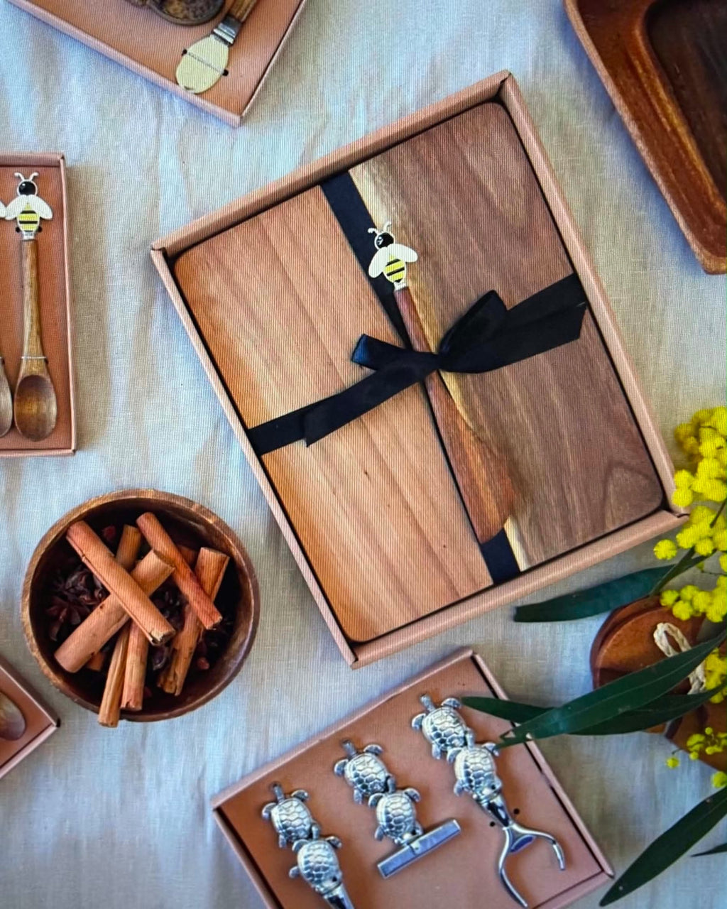 Thrift N Gift acacia wood cheeseboard set with a decorative bee spreader, presented in a gift box with a black ribbon.