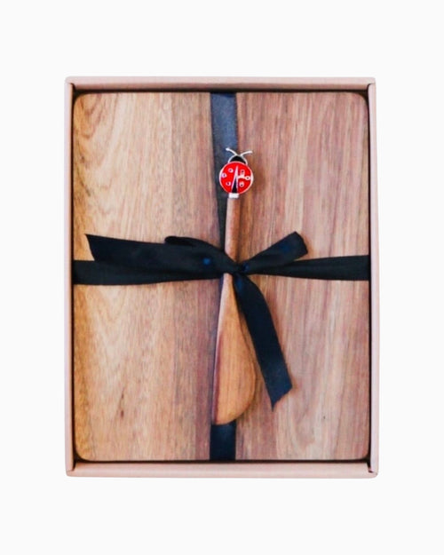 Thrift N Gift acacia wood cheeseboard set with a decorative lady beetle spreader, tied with a black ribbon in a box.