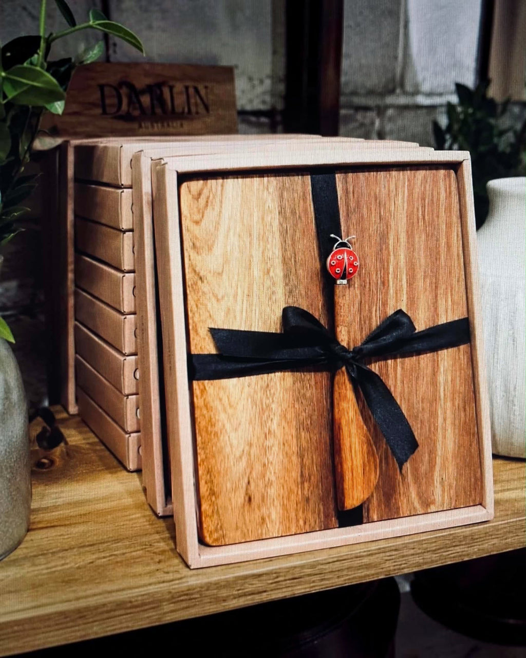Thrift N Gift acacia wood cheeseboard set with a decorative lady beetle spreader, tied with a black ribbon in a box.