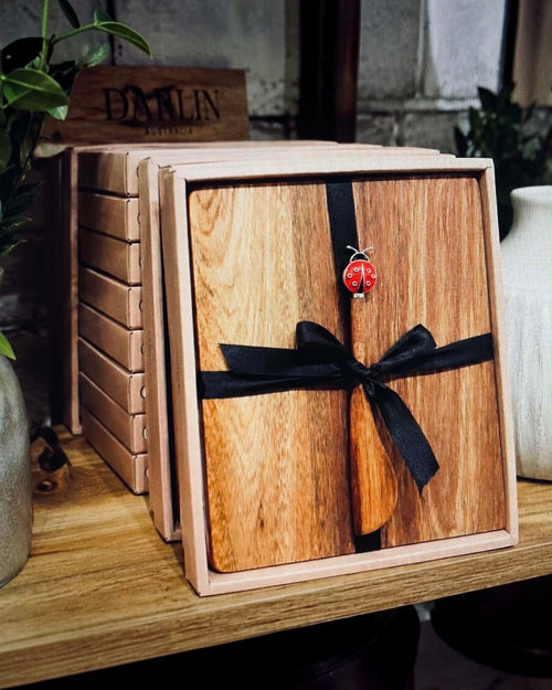 Thrift N Gift acacia wood cheeseboard set with a decorative lady beetle spreader, tied with a black ribbon in a box.
