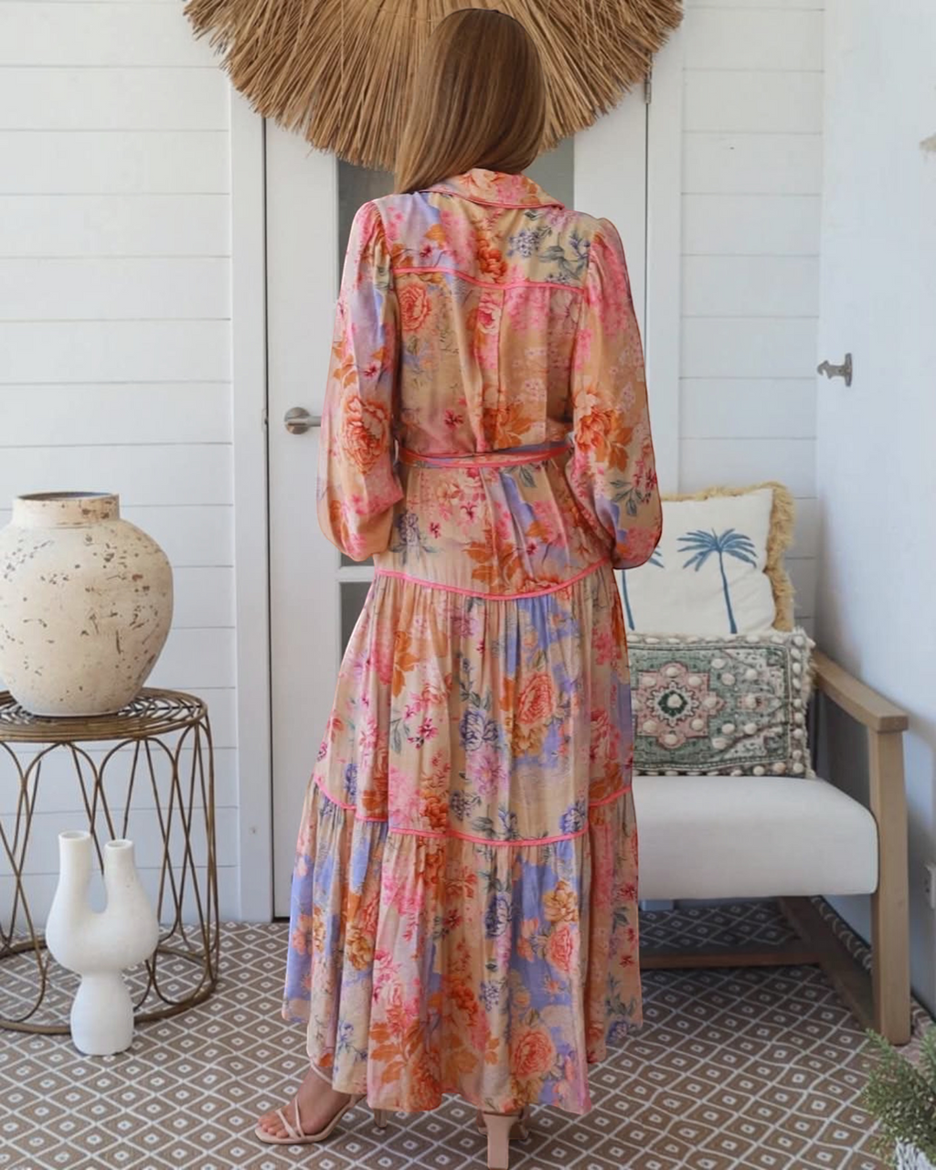 Back view of a woman wearing a Thrift N Gift floral maxi dress with tiered skirt, long sleeves, and contrast piping.