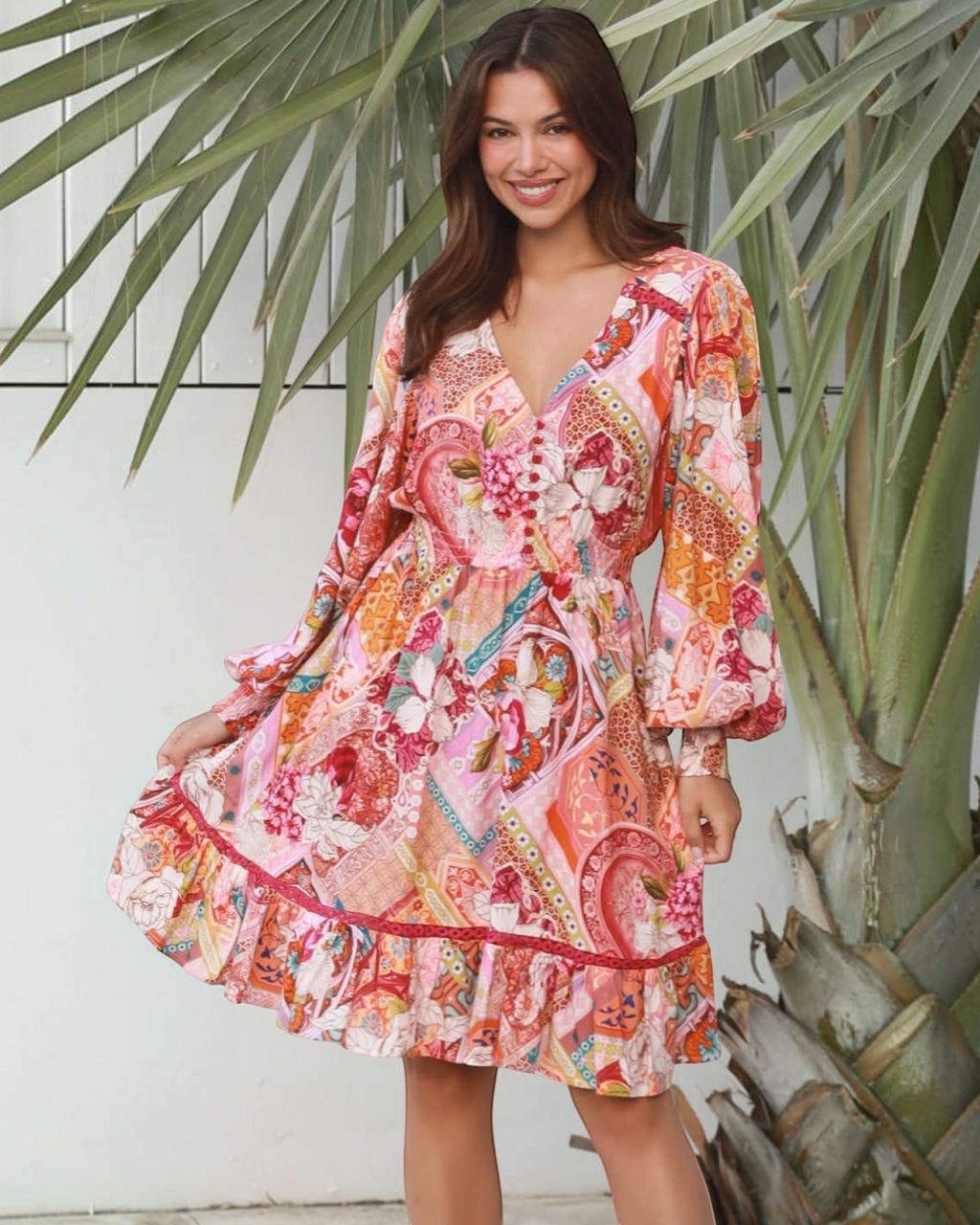 Thrift N Gift long sleeve mini dress with vibrant floral patchwork print, V-neck, and ruffled hem in a tropical setting