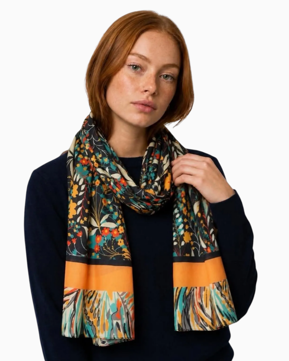 Thrift N Gift lightweight scarf with dark floral print in orange, teal, and gold, worn by a woman in a navy sweater.