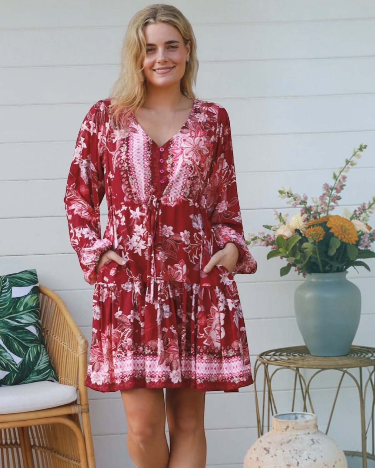Thrift N Gift red floral print long sleeve mini dress with a V-neck, button-down front, and side pockets on a model.